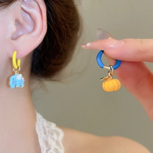 Detail of asymmetrical earrings with blue elephant and orange pumpkin pendants