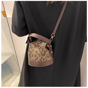 Detail view of the leopard print cylinder bucket bag with adjustable dark brown strap