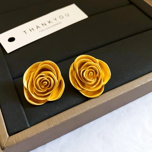 Gros plan de boucles d'oreilles roses en or mat sur un plateau à bijoux en velours noir