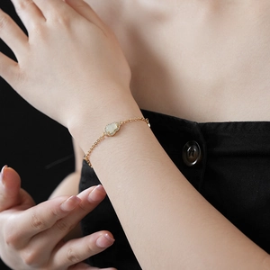 Close-up of gold chain bracelet with zircon-encrusted jade gourd charm on wrist