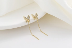 Macro detail of golden butterfly tassel earrings with sparkling pavé cubic zirconia