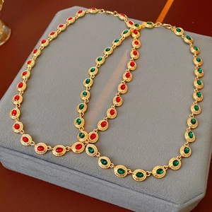 Détails de colliers dorés vintage avec pierres ovales rouges et vertes sur velours gris