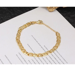 Detail of gold-tone anchor chain bracelet featuring a lobster clasp and extension