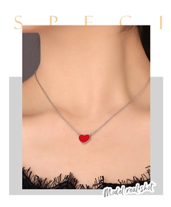 Close-up of a heart-shaped enamel pendant on a silver chain worn by a female model