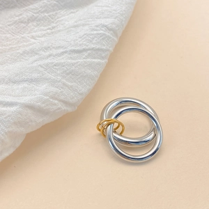 Close-up of interlocking gold and silver geometric rings with a polished mirror finish