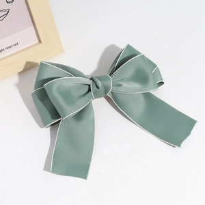 Detailed view of Morandi green bow hair clip with white stitching and satin texture