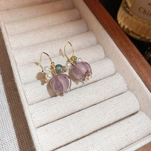 Detailed macro shot of floral drop earrings with purple petals and white pearls