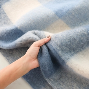 Close-up of soft blue plaid cashmere-like scarf texture showing thickness and fringe
