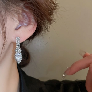 Gros plan de boucles d'oreilles pendantes argentées en forme de U avec cristaux sur le modèle