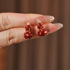 Detail of 18k gold plated gourd earrings with red enamel and golden accents