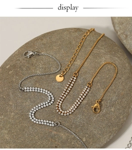 Detail of double-row zircon anklets in gold and silver finish on natural stone