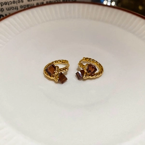 Detailed view of gold plated twisted hoop earrings featuring square brown zircon stones