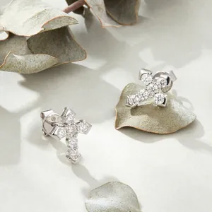 S925 sterling silver cross stud earrings with sparkling cubic zirconia on stone surface