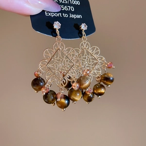 Detail of vintage hollow flower earrings with tiger eye beads and pink crystals