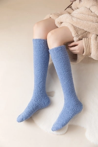 Detail of blue coral fleece knee-high socks on a model for warm winter lounge wear