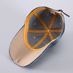 Vue détaillée de la casquette en jean avec liseré jaune et boucle en cuir au dos