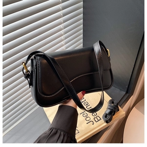 Detail of black vintage shoulder bag with golden hardware and textured faux leather
