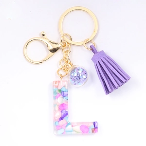 Close-up of resin letter L keychain with purple tassel and colorful stones
