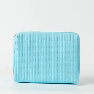 Detail view of sky blue quilted makeup bag with vertical stripes and top zipper