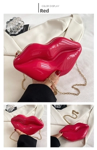 Detail view of a bright red lip-shaped acrylic clutch bag with a sleek gold chain strap