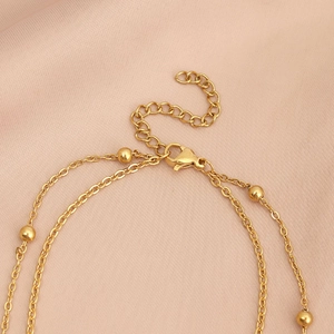 Detail of gold layered necklace featuring polished beads, lobster clasp and extension chain