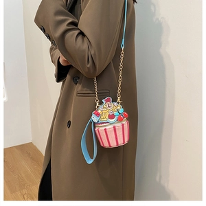 Model wearing a creative small cake shaped crossbody bag with colorful stripes and chain strap