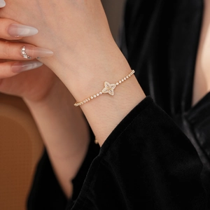 Macro shot of gold four-leaf clover bracelet with sparkling zircons on a model's wrist
