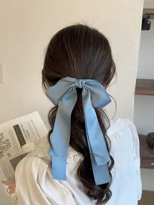 Nœud papillon en satin bleu clair avec longs rubans sur cheveux longs ondulés
