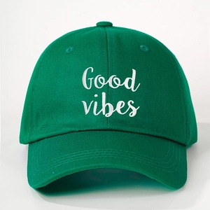 Close-up of green cotton baseball cap with white Good Vibes embroidery and stitching