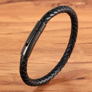 Braided black leather bracelet with black magnetic clasp on natural wooden surface