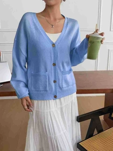 Detail view of light blue V-neck knit cardigan with brown buttons and front pockets