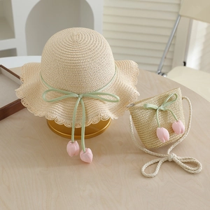 Close-up of kids straw sun hat and matching bag set with green ribbon and pink tulip accents