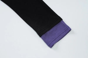 Détail de la manche en tricot noir avec revers côtelé violet et coutures fines