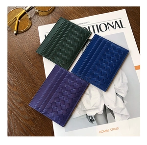Slim woven sheepskin card holders in green, blue, and purple on a wooden table