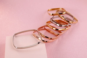 Close-up of square polished stainless steel bangles in gold, silver, and rose gold
