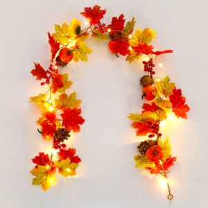 Close-up of autumn garland with pumpkins, maple leaves, berries, and warm LED lights