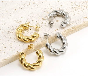 Detail von gedrehten Seil-Creolen in Gold und Silber auf einer Steinplatte
