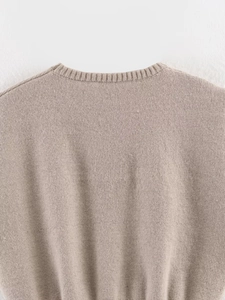 Detailed close-up of a beige knit vest featuring a ribbed crew neck and soft texture