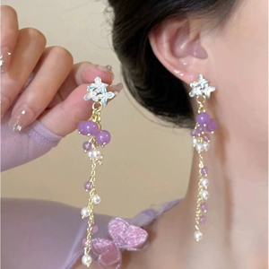 Detailed close-up of elegant purple bead tassel earrings with white pearls on a model