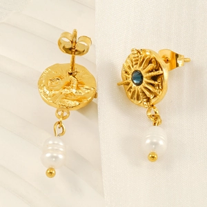 Detailed macro view of gold sun drop earrings featuring blue gems and baroque pearls