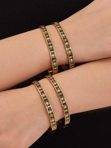 Macro shot of gold bracelets stacked on wrist featuring rectangular multi-color crystals