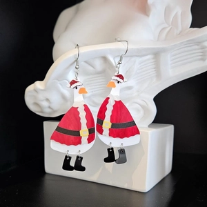 Cute Christmas duck acrylic earrings with festive red hat shown on a white display