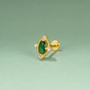 Macro shot of gold ear stud with green oval stone and sparkling diamond accents