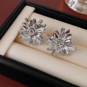 Detail of silver floral earrings with sparkling zircon center in a black leather box