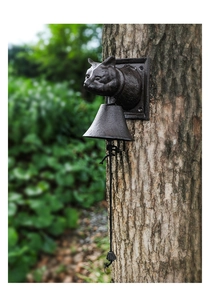 Close-up of vintage cast iron owl doorbell mounted on a rustic tree trunk with rope