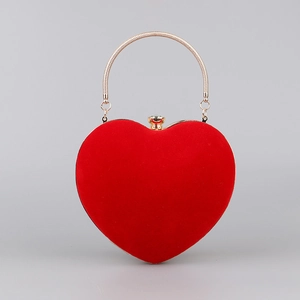 Detail of red heart-shaped velvet evening bag with round golden metal handle