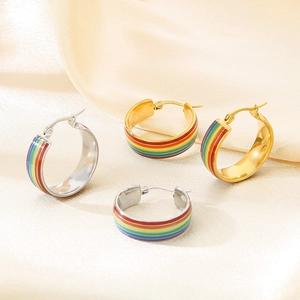 Draufsicht auf Regenbogen-Creolen in Gold und Silber auf seidigem Stoffhintergrund