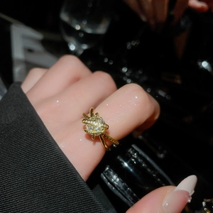 Close-up of a gold criss-cross ring featuring twisted texture and a large zircon center stone