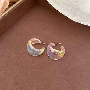 Macro detail of iridescent C-shaped acrylic earrings with colorful holographic finish