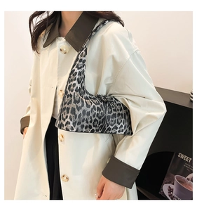 Detailed view of leopard print shoulder bag worn with a beige coat in a minimalist setting